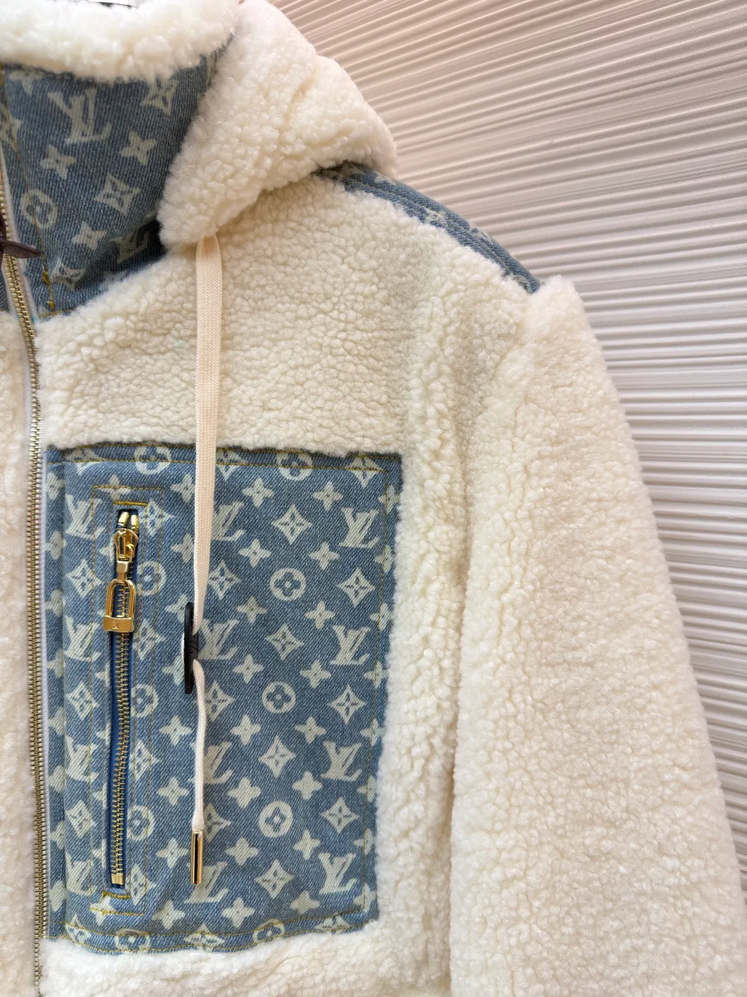 LOUIS VUITTON Letter jacquard splicing lamb wool ski hooded jacket ●Original version: purchased and developed by 26909 ●Item number: 1682241-C35 ●Fabric: lamb wool fabric ●Technology: jacquard production ●Color: off-white ●Version: fitted version ●Weight: about 1245 grams ●Size: 34-36-38-40-42-44 ●Description: The main body of this lamb wool spliced denim jacket is made of imported imitation lamb wool fabric, which has been processed by carding and shaping processes. The wool feels fluffy and soft and is not easy to shed and pill. The fabric has a uniform weight and has both warmth retention and breathability. The neckline, placket and chest pockets are spliced ​​with classic presbyopic denim. The denim is enzymatically washed to create a natural aged texture. The presbyopic pattern is embossed, making the texture three-dimensional and not easy to fall off. The body adopts a loose hooded fit, with a built-in shaping lining on the brim and an adjustable drawstring design; a custom metal zipper is used at the placket, and the chain teeth are gold-plated for smooth pulling and anti-oxidation. The edges of the pockets are reinforced with double stitching, and the splicing of lambswool and denim is made by hand caulking. The stitching is fine and smooth. Every detail is strictly controlled, showing the craftsmanship and quality of high-end clothing. The overall wiring is straight and delicate, the fabric is comfortable and soft, and the color is consistent without color difference. It can be matched with the same style to create a fashionable look and control various occasions. Customized accessories, complete with three standards, same style for men and women!